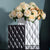 Deux vases rectangulaires noir et blanc avec bouquet de fleurs posés sur une table noire.