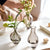 Plusieurs soliflores en verre avec fleurs posés sur une table.