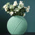 Vase vert rond avec bouquet de fleurs posé sur une table noire.