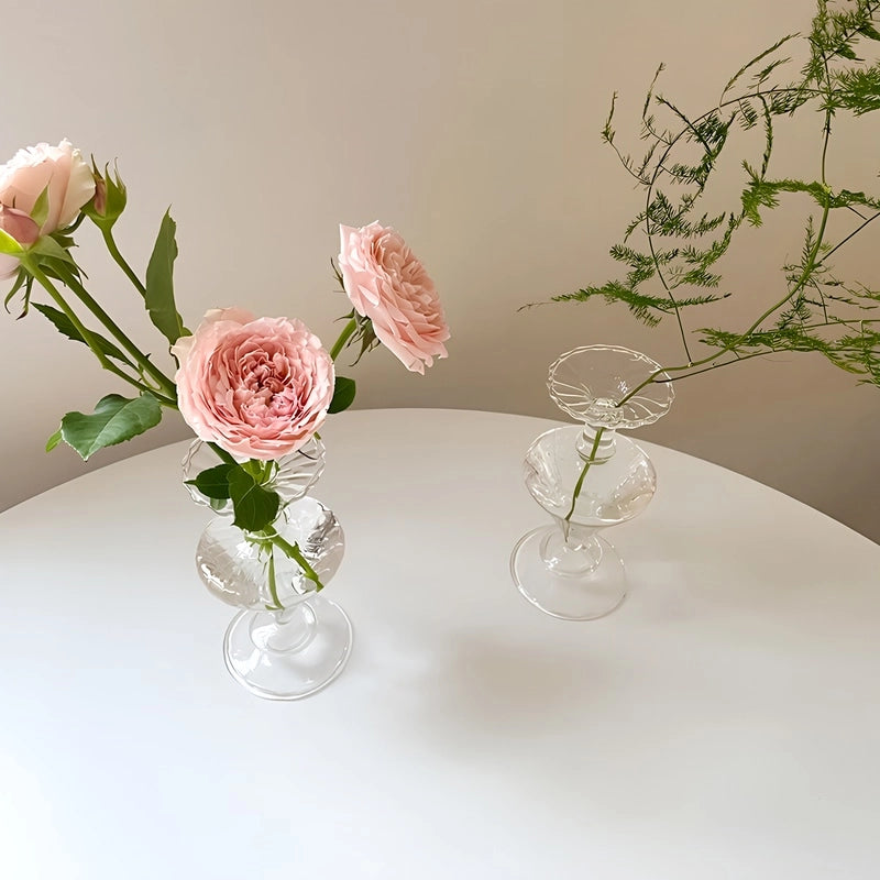 Présentation de deux vases carafe chic transparent en verre avec fleurs sur une table.
