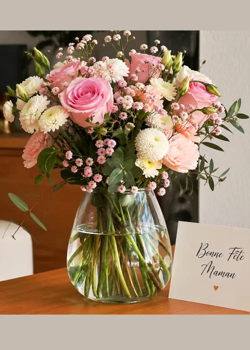 Présentation d'un vase sur une table avec des fleurs avec un mot bonne fête maman.
