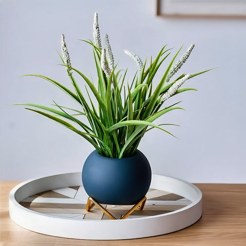 Soliflore boule colorée sur trépied en céramique, présentation du modèle bleu sur table orné d'une plante verte fleurie. 