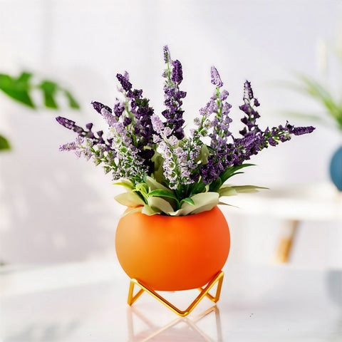 Soliflore boule colorée sur trépied en céramique, présentation du modèle orange sur une table avec un bouquet de lavandes.