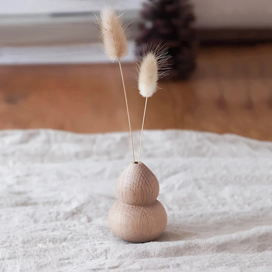 Soliflore Gourde Wu Lou en Bois présentation avec deux fleurs de phalaris sur un chemin de table blanc.