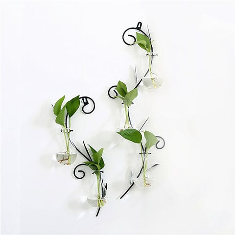 Soliflore mural en forme d'arabesque avec mini vases transparents sur un mur blanc modèles S et M avec des plantes