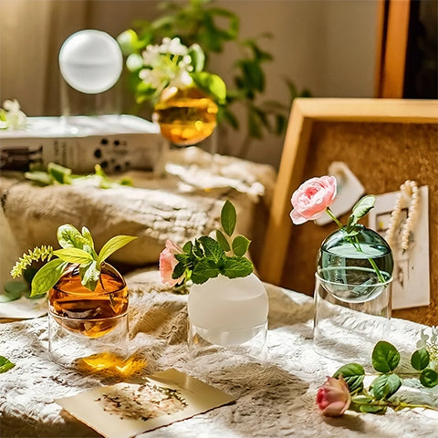 Soliflore sphérique sur socle tubulaire en verre présentation de tous les modèles avec fleurs sur une table