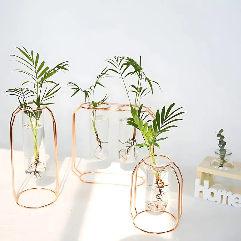 Soliflore Tube Suspendu Cadre Géométrique Rose Gold, présentation de tous les modèles avec plantes vertes en hydroponie et ornement sur une table blanche.