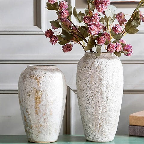 Vase  céramique artisanale effet pierre poreuse modèles M et L avec fleurs sur une table