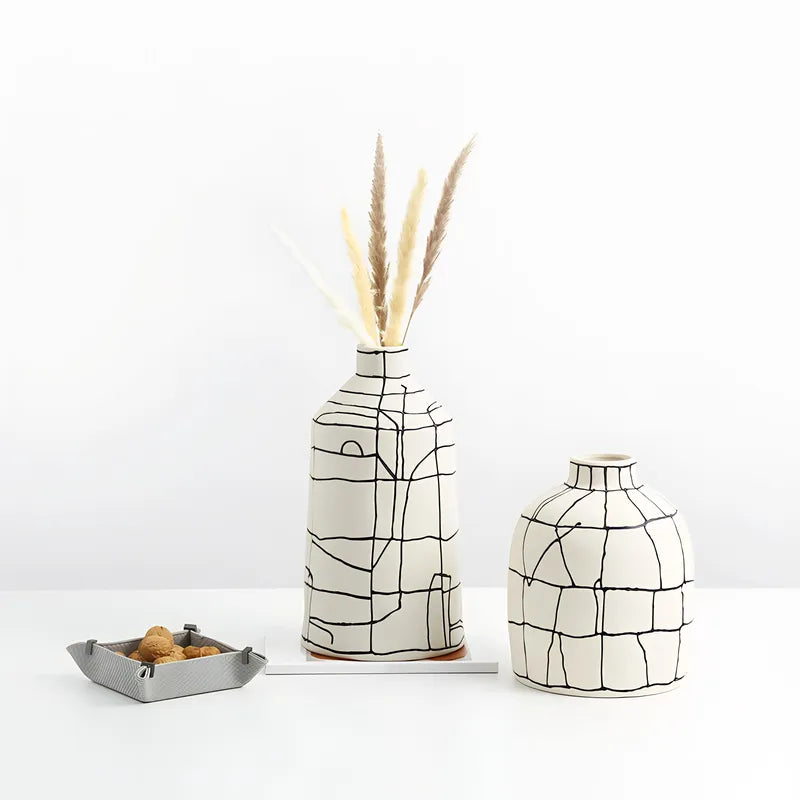 Vase Artistique Blanc aux Lignes Abstraites Noires présentation des modèles A avec fleurs séchées et B sans fleurs sur une table blanche.