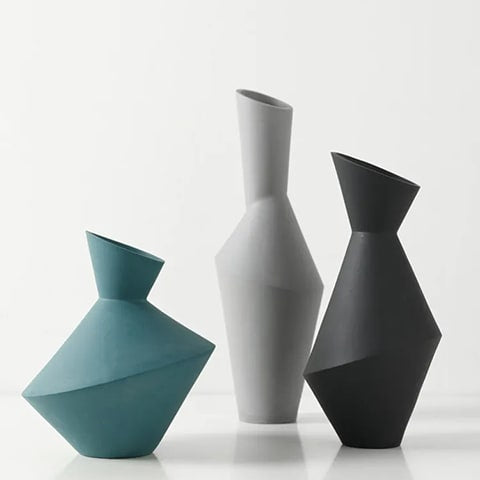 Vase asymétrique en céramique modèles Noir et Vert et Gris sur une table blanche