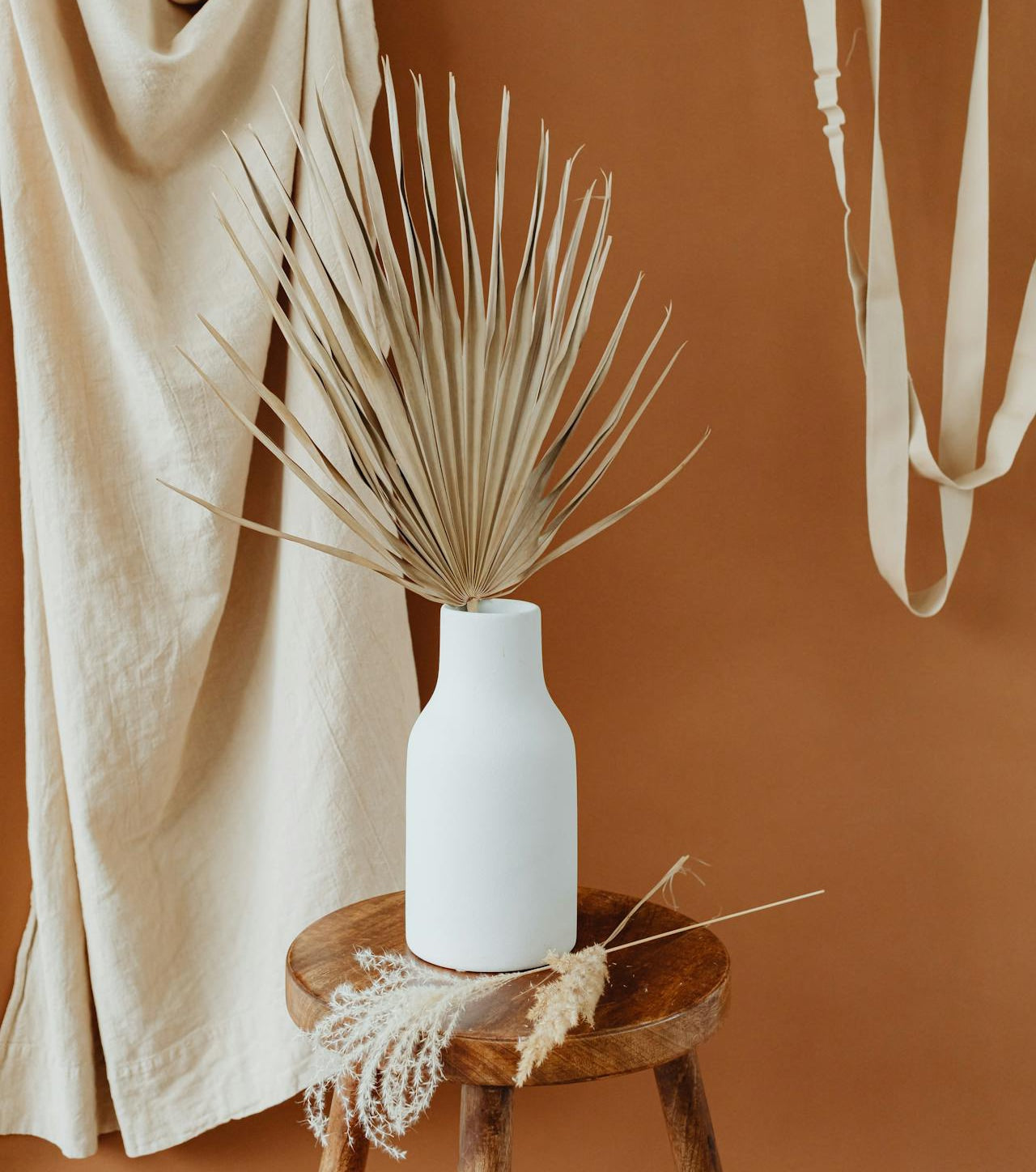 Vase blanc design en céramique sur une chaise présentation avec fleurs séchées et ornements