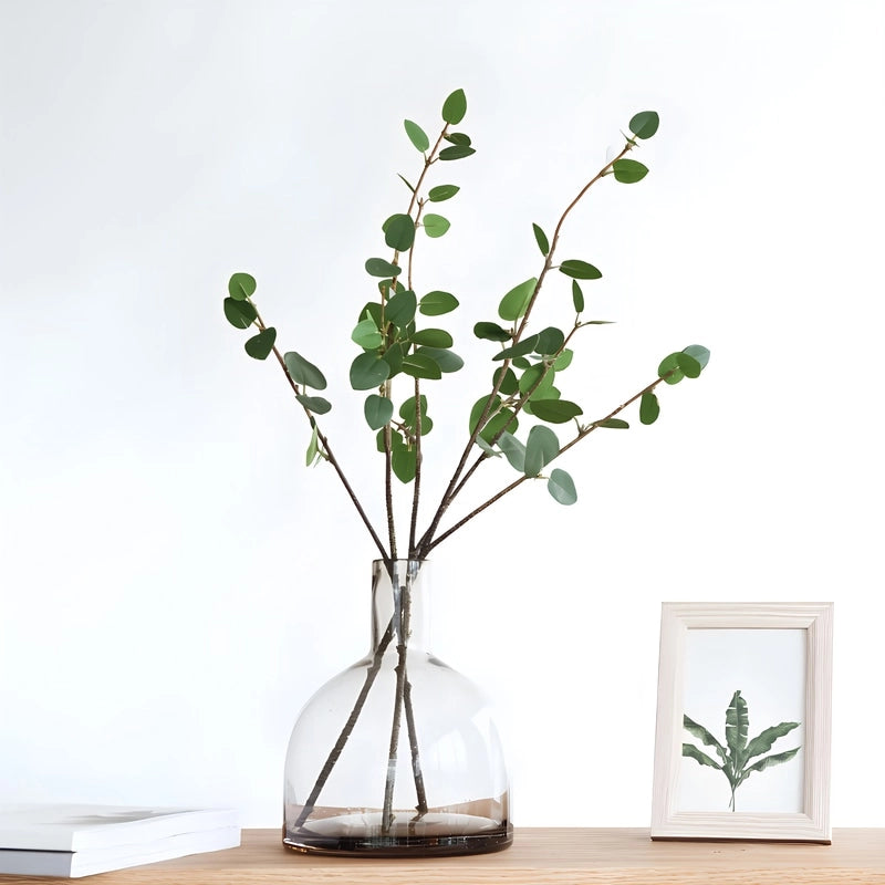 Vase Bouteille Verre Bullé Coloré en verre, présentation sur une table du modèle B marron avec feuillages verts.
