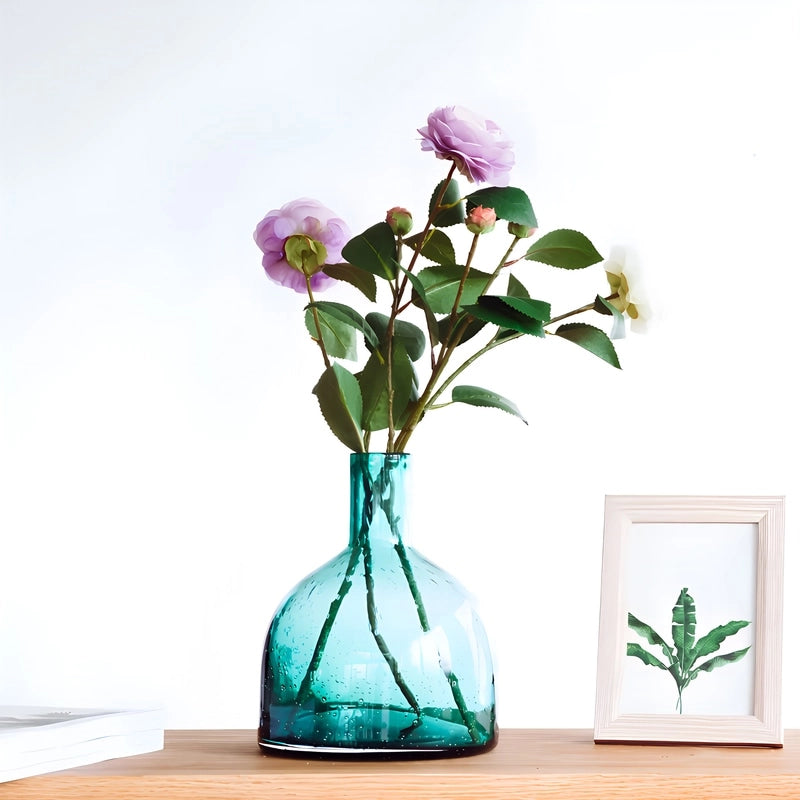 Vase Bouteille Verre Bullé Coloré en verre, présentation sur une table du modèle B vert avec bouquet de fleurs.