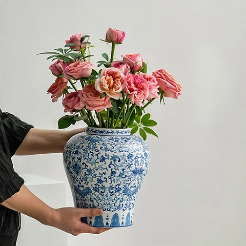 Vase chinois bleu et blanc motif fleurs en Porcelaine, présentation tenu en main du modèle M avec bouquet de roses.