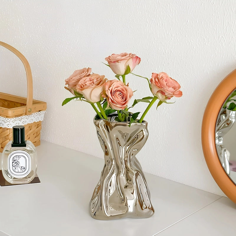 Vase Créatif Froissé Design Original présentation du modèle argenté avec des roses sur une table.