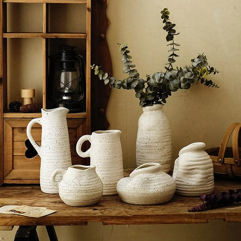 Vase cruche vintage blanc moucheté en céramique présentation tous les modèles avec des branches d'eucalyptus sur une table en bois dans un salon