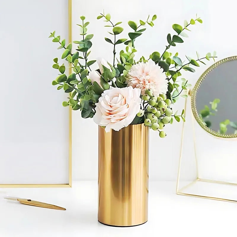 Vase doré cylindrique en métal, présentation du modèle petit avec bouquet de fleurs sur une table blanche.