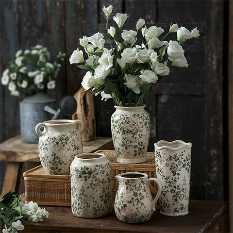 Vase d'époque motif feuillages verts présentation de tous les modèles sur une table en bois avec bouquet de fleurs blanches
