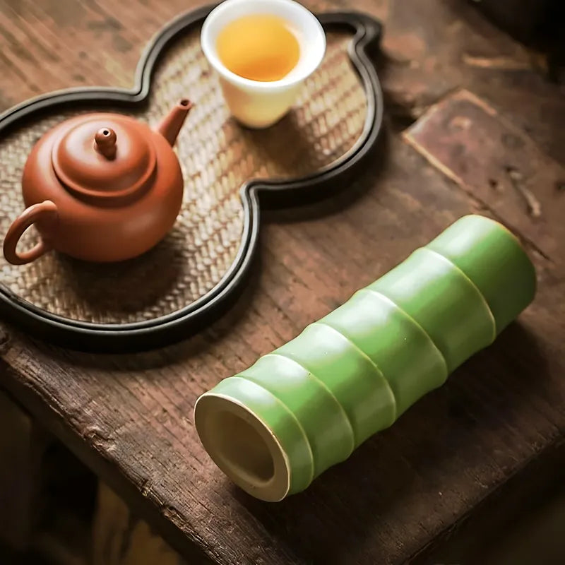 Vase Forme Bambou Vert, présentation couché sans fleurs sur une table en bois, à côté d'un plateau de service à thé, vue de haut.