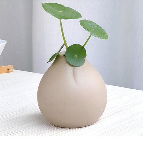 Vase en grès beige en céramique présentation du modèle B sur une table avec plantes vertes