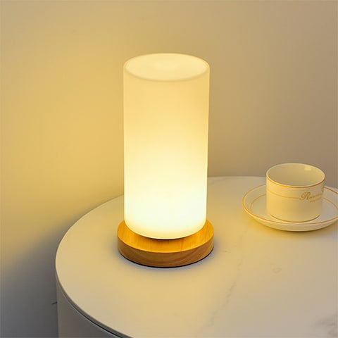 Vase lampe romantique pour fleurs séchées, présentation du modèle rond allumé sans fleurs sur table de nuit, à côté d'une tasse.