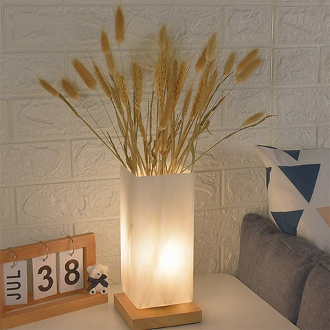 Vase lampe romantique pour fleurs séchées, présentation du modèle carré allumé, sur une table de chevet, orné de blés séchés.