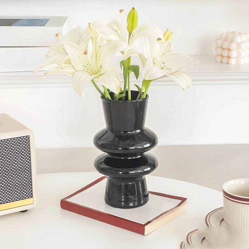 Vase Nordique Double Anneaux présentation du modèle noir avec des lys sur un meuble blanc.
