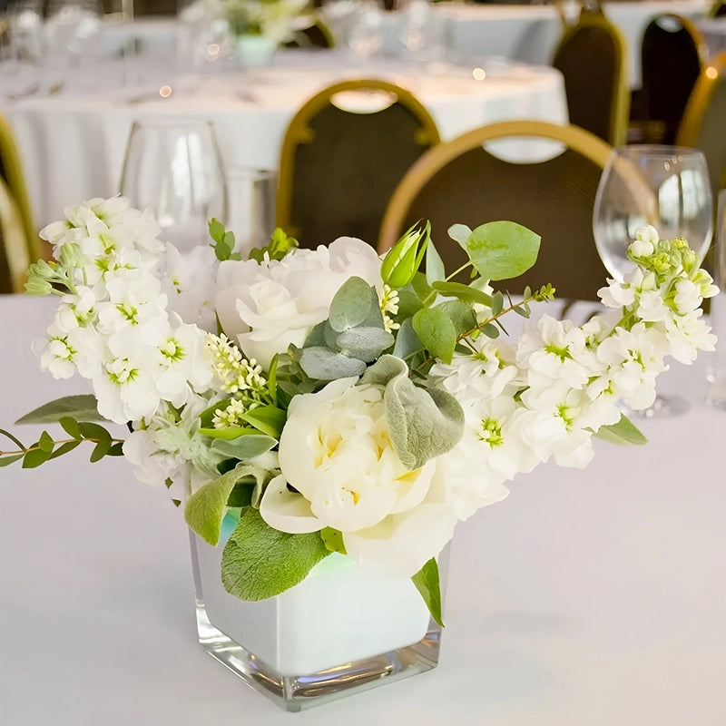 Vase Petit Cube Décoratif Transparent avec bouquet de fleurs blanches sur une table de mariage.