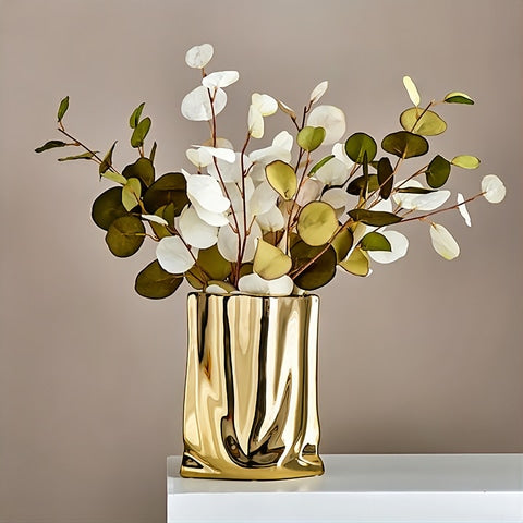 Vase Plissé Élégant Or ou Argent en céramique présentation du modèle doré avec bouquet d'eucalyptus séchés sur un meuble.