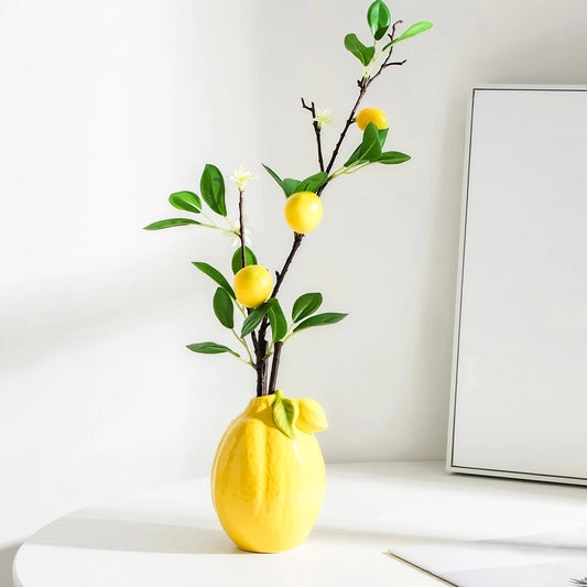 Vase Soliflore Original Forme Citron, présentation avec tige artificielle de citron sur une table blanche.
