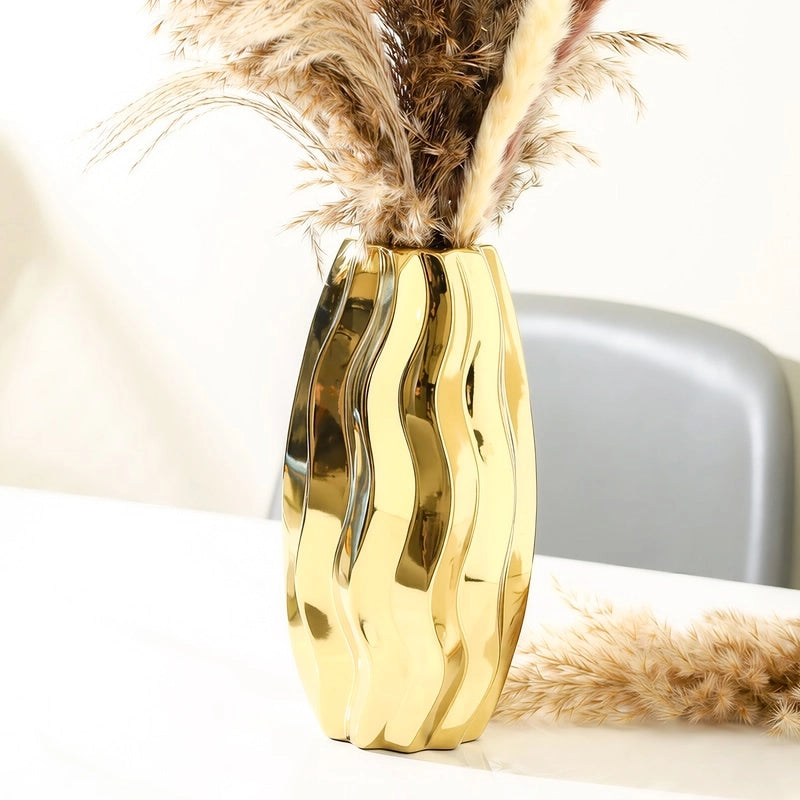 Vase Sophistiqué Doré Lignes Verticales Ondulées mise en scène avec bouquet de fleurs séchées sur une table blanche.