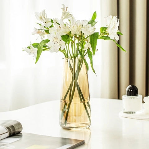 Vase translucide reflet irisé en verre modèle Ambre posé sur une table blanche avec bouquet de fleurs blanches