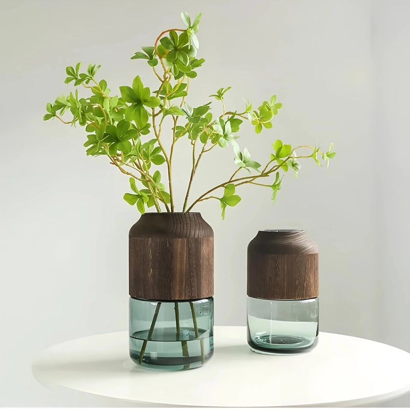 Vase Tubulaire Transparent Bi-Matières présentation des modèles Grand avec tiges florales et Petit sur une table blanche.