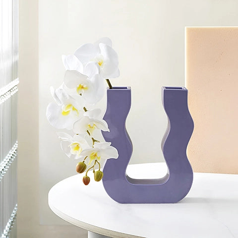 Vase U ondulé couleurs variées en céramique présentation du modèle Violet Petit avec hampe d'orchidées sur une table