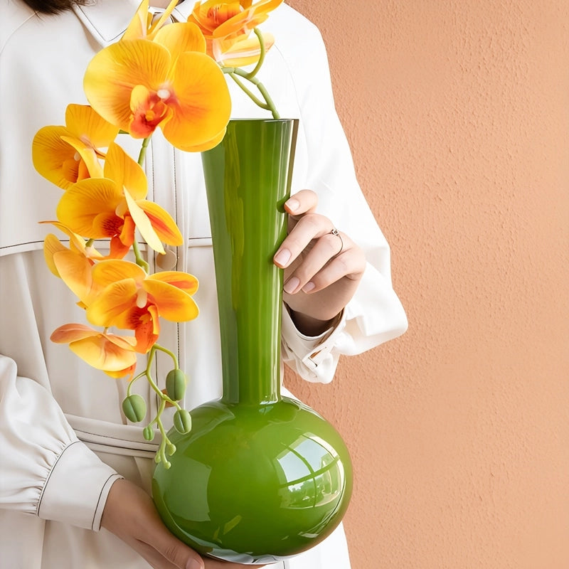 Vase Vert Boule au Col Élancé, présentation du modèle petit, tenu en main, orné d'une hampe d'orchidées.