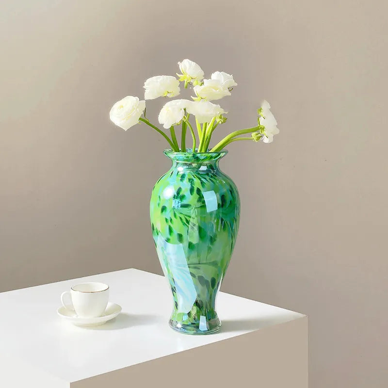 Vase Vert Émeraude Raffiné Motif Abstrait présentation avec bouquet de fleurs blanches sur une table blanche.