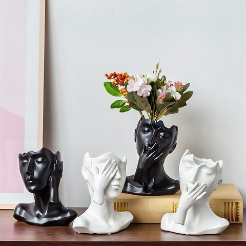 Vase visage femme esthétique en céramique présentation des modèles  C, A noir et C, B blanc sur une table avec fleurs
